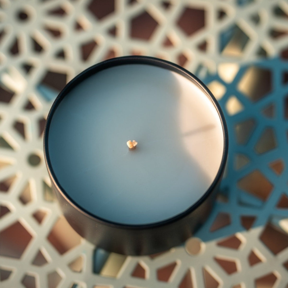 Organic candle a in black cylindrical container on a decorative surface, branded 'The Organic Candle Co'.