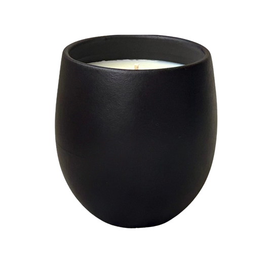 Organic candle in black ceramic vessel on a neutral background