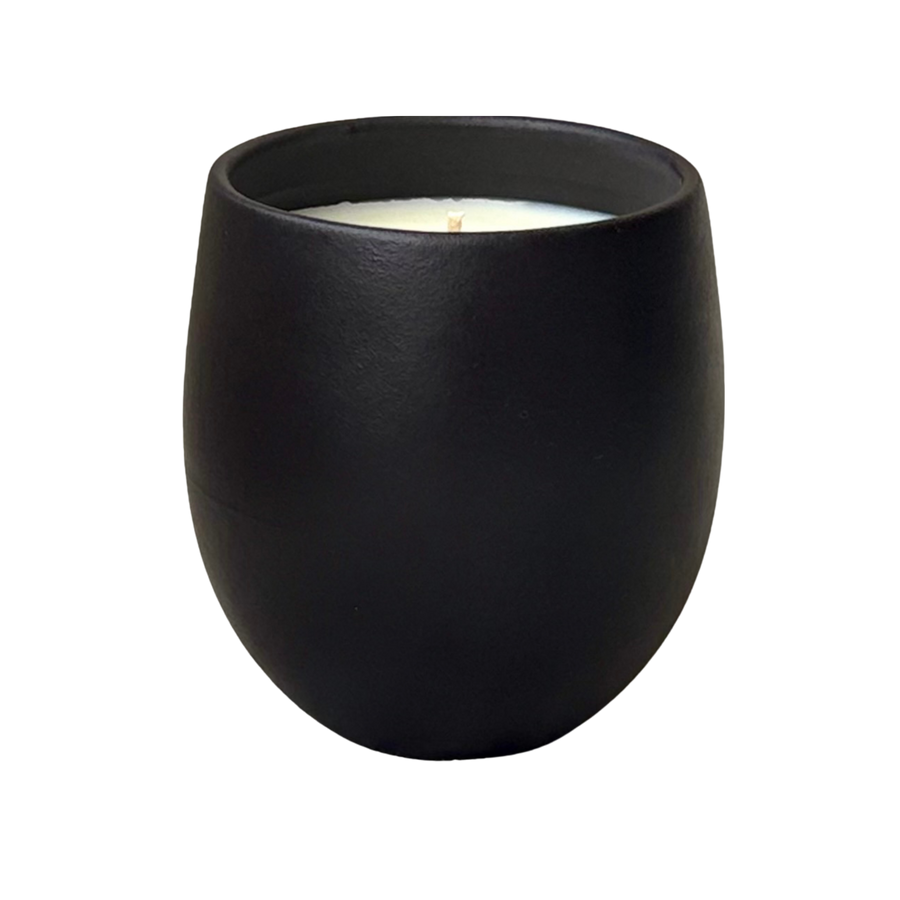 Organic candle in black ceramic vessel on a neutral background