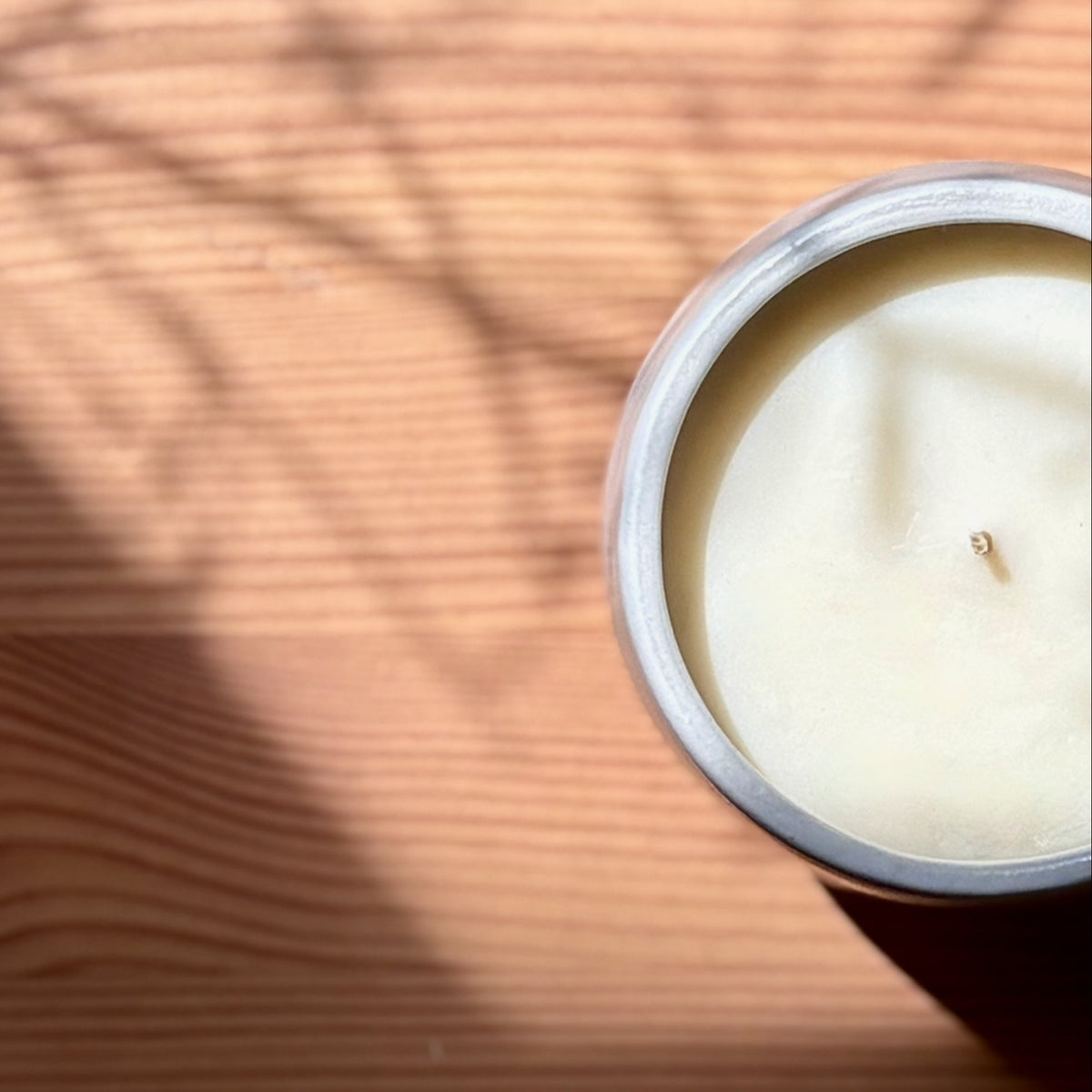 Candle on a wooden surface with 'The Organic Candle Co.' branding.