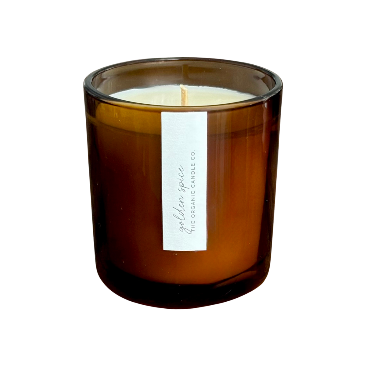 An organic candle in an amber glass jar candle with a white paper label reading 'golden spice THE ORGANIC CANDLE CO.' on a plain white background.