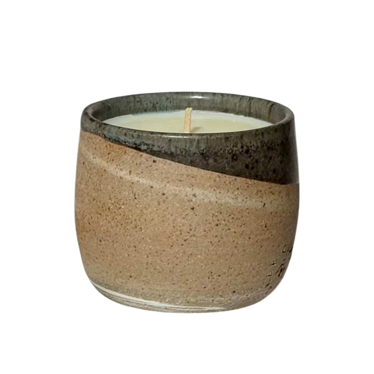 An organic candle in a hand-made stoneware cup with a diagonal split design. The lower half is a speckled warm beige, while the upper half is a dark, glossy charcoal gray.