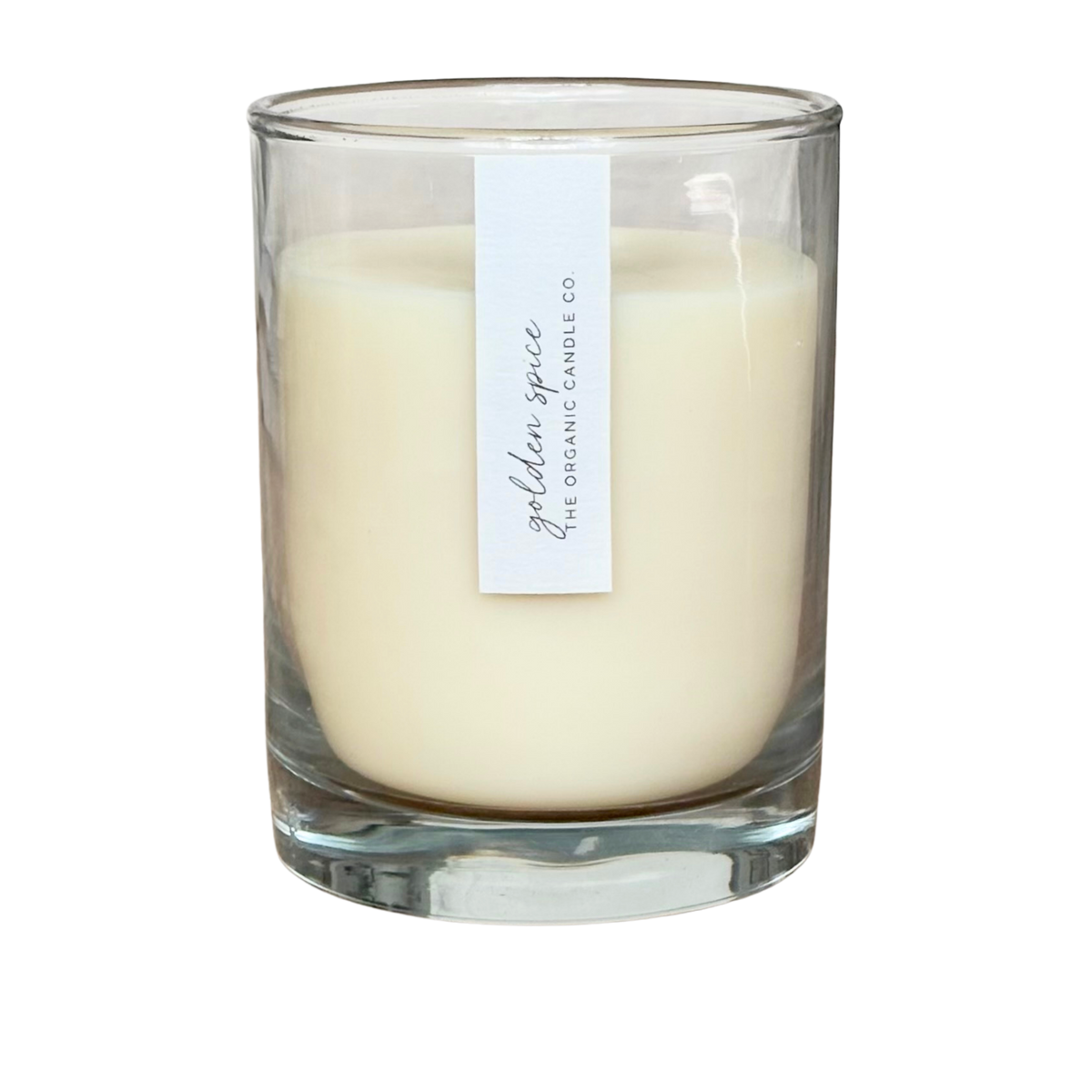 An organic candle in a clear glass jar filled, featuring a vertical white label that reads 'golden spice' and 'THE ORGANIC CANDLE CO.' on a plain white background.