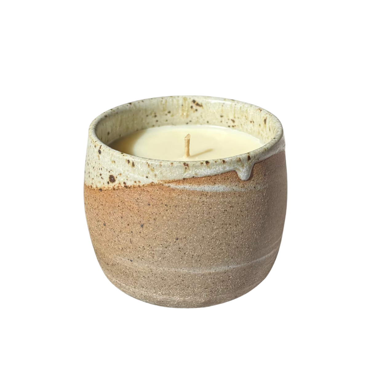 An organic candle in a handmade stoneware cup, set against a plain white background.