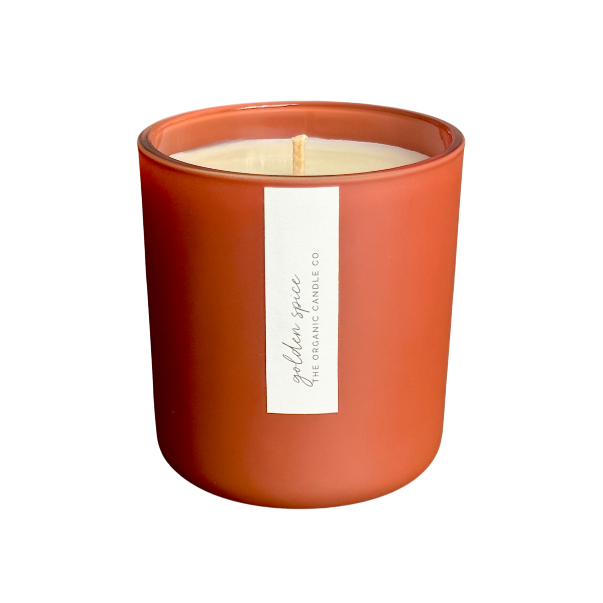 An organic candle in a matte terracotta-colored glass jar with a vertical white label reading 'golden spice THE ORGANIC CANDLE CO.' on a plain white background.